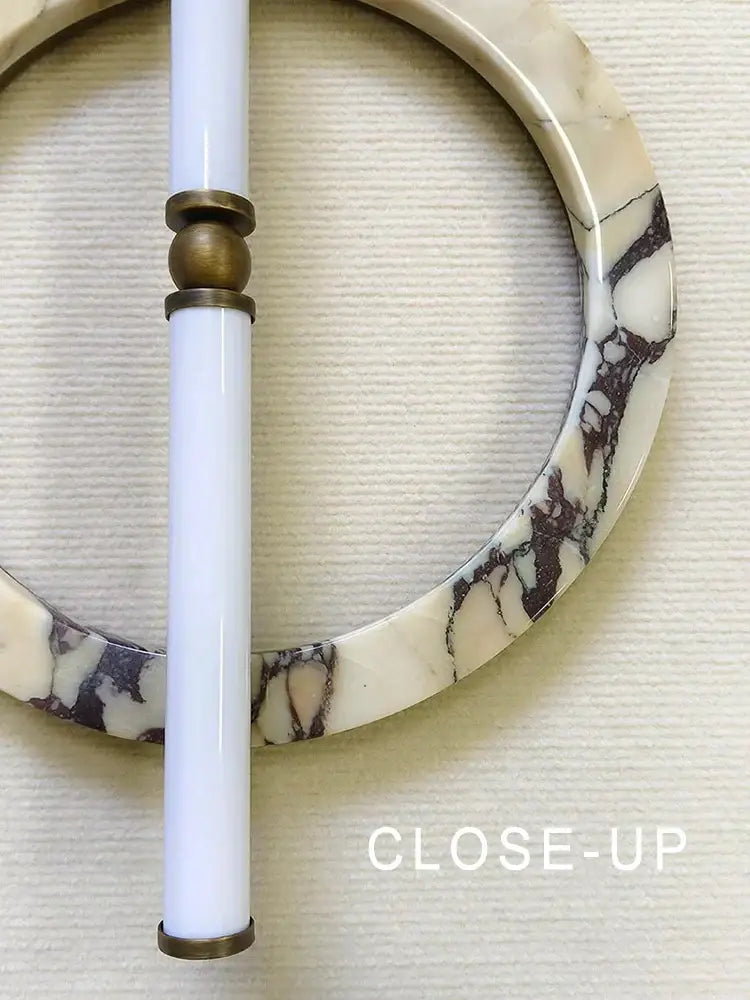 A white marble bangle with dark veining and brass fittings displayed alongside a modern green black marble wall lamp bedroom sconce