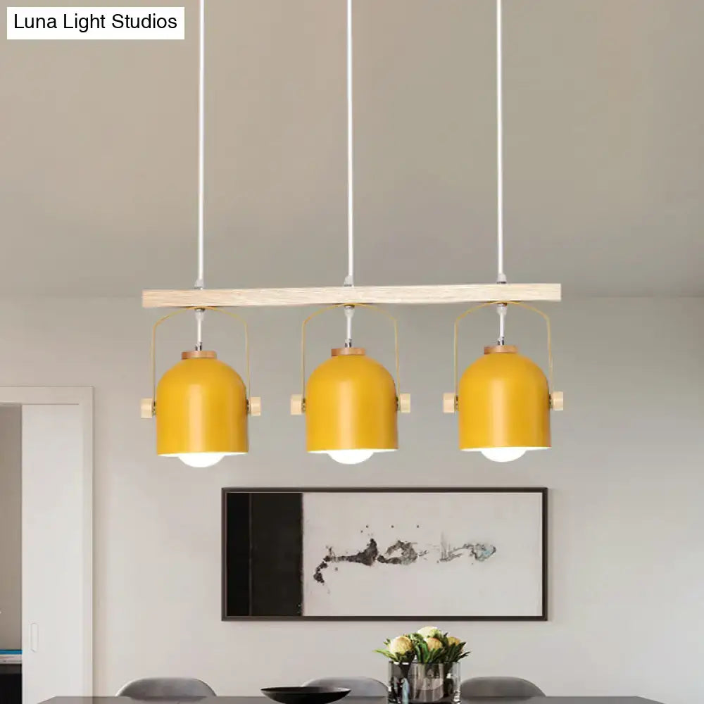 Modern yellow dome island light with three metal dome shades suspended from a wooden bar by decorbites
