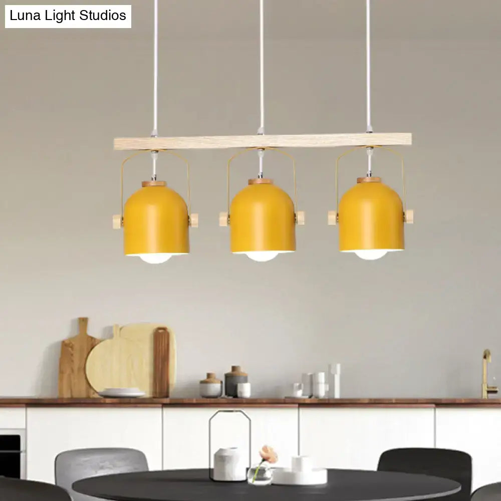 Modern yellow dome island light with three metal dome shades suspended from a minimalist wooden bar chandelier