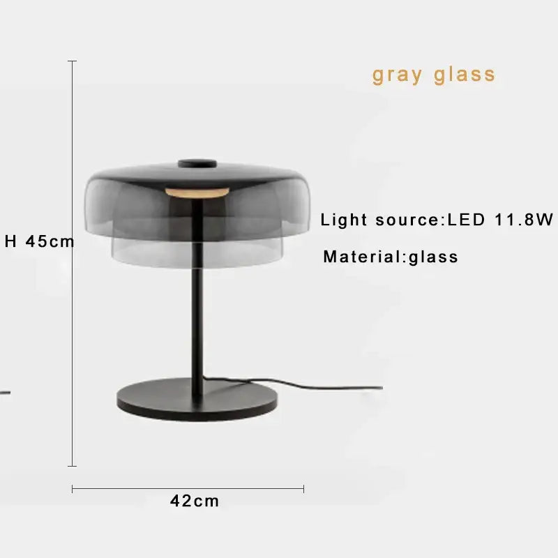 Modern table lamp with sleek translucent gray glass shade and black metal base for bedroom use featuring led bulb