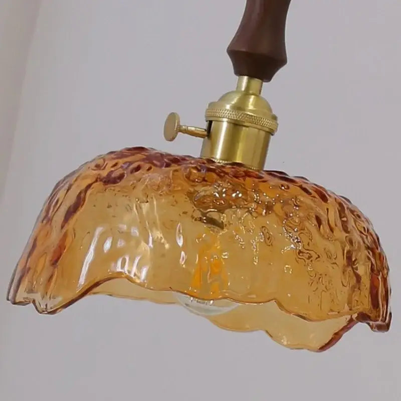 Modern amber-colored glass walnut wood pendant light with brass fixture and dark wood handle for dining room use