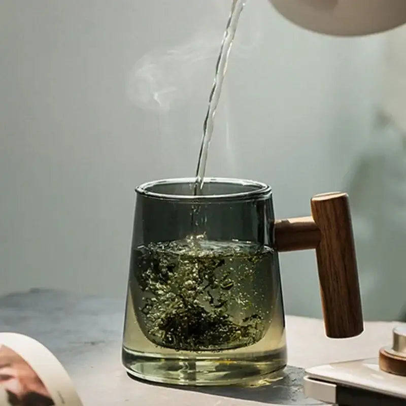 Modern green and gray glass tea cup with wood handle filled with steaming green tea by decorbites glass tea