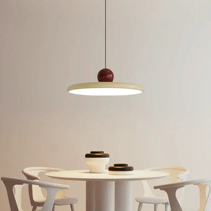 A modern pendant light with a matte cream wind saucer shade and a glossy red spherical top for dining room decorbites cream wind