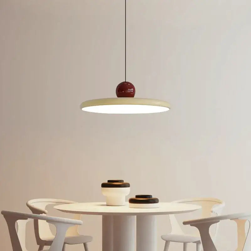 A modern pendant light with a matte cream wind saucer shade and a glossy red spherical top for dining room decorbites cream wind