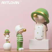 Modern green and white polka dot bubble gum blowing statue wearing a green hat with gold trim for living room decor