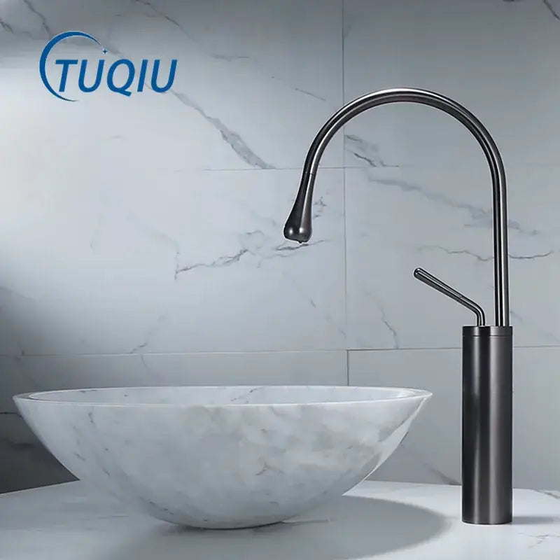 Modern gun grey brass basin faucet with sleek curved spout and cylindrical base beside white marble sink decorbites gun grey