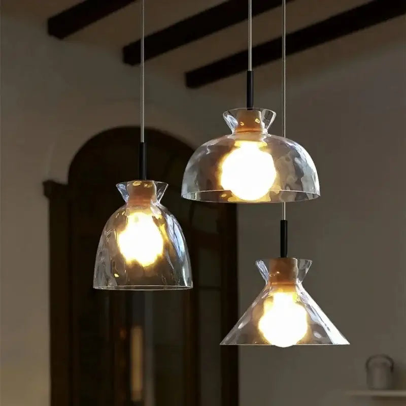 Three modern decorbites clear glass pendant lamps with hammered shades and black metal fixtures for kitchen lighting