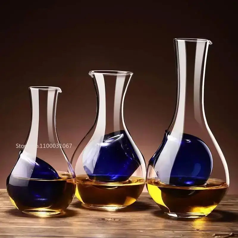 Three clear glass wine decanters with amber liquid and blue spheres in modern decorbites crystal glass set for dining room
