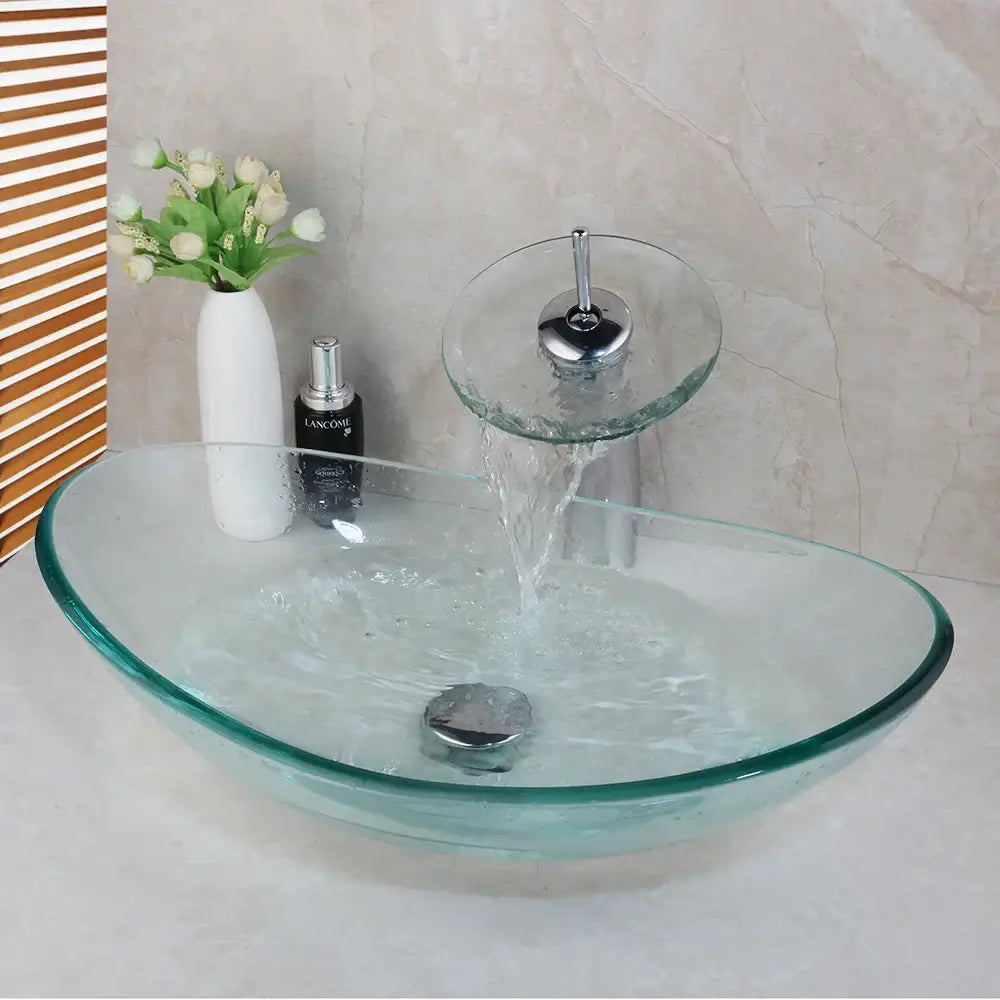 Clear glass oval sink with matching transparent waterfall basin mixer faucet featuring chrome accents for bathroom