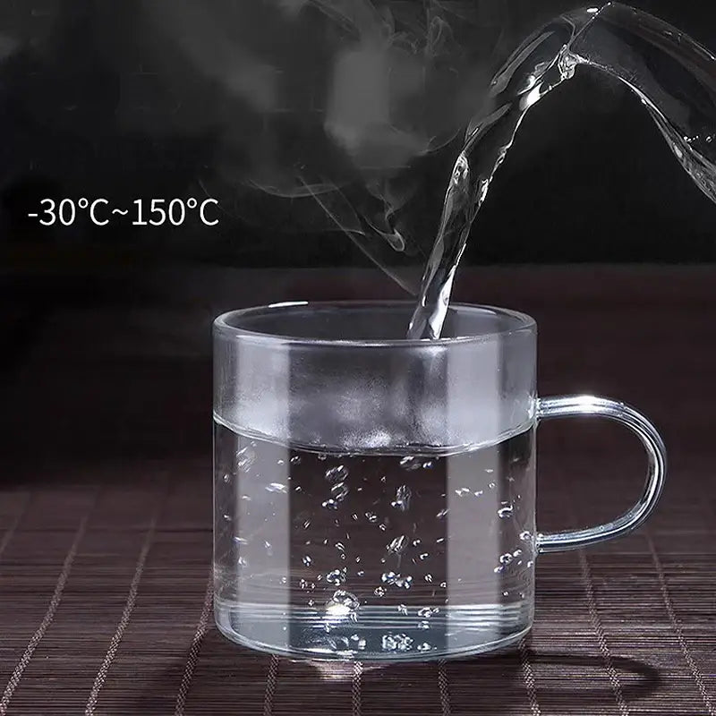 Modern heat resistant clear glass tea cup set featuring a transparent handle filled with steaming water