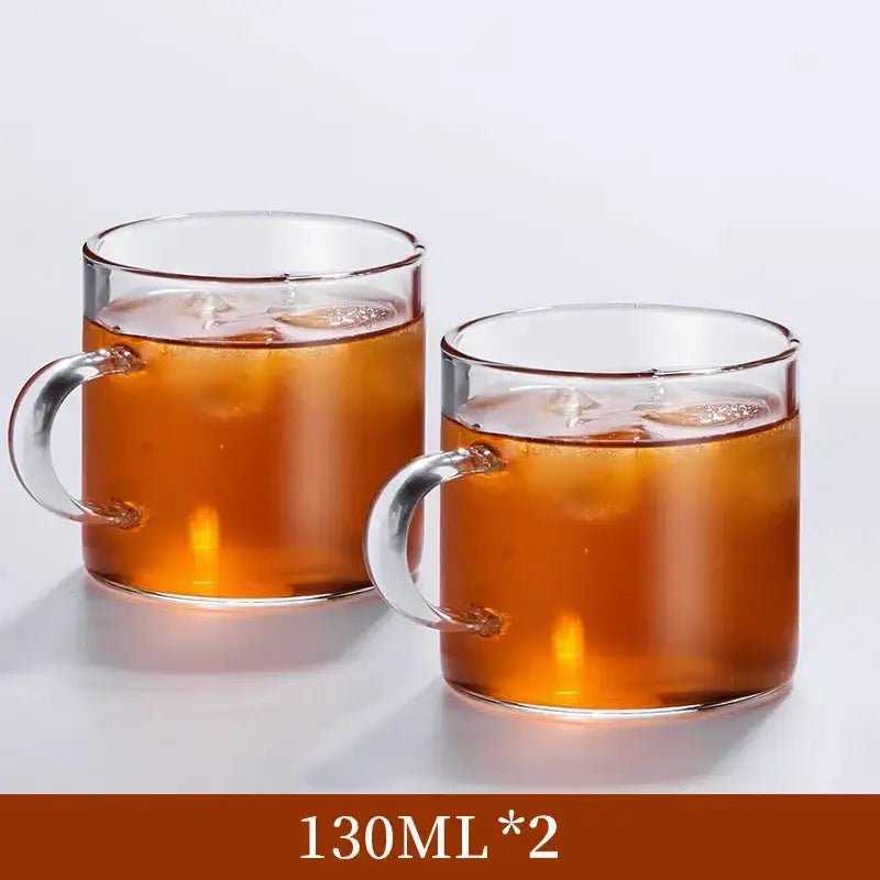 Modern heat resistant clear glass tea cup set with sturdy handles filled with iced amber beverage for dining use