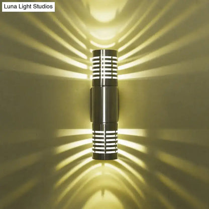 Modern black metal wall mounted led sconce with hollow design and horizontal slats casting warm radiant light patterns