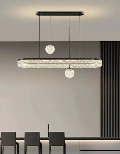 Modern oval-shaped led chandelier with black frame and crystal accents flanked by spherical glass pendant lights for indoor lighting