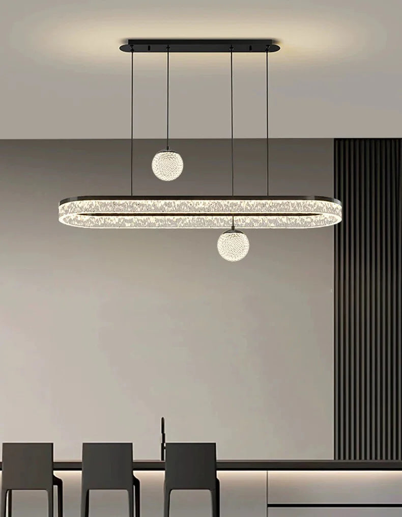 Modern oval-shaped led chandelier with black frame and crystal accents flanked by spherical glass pendant lights for indoor lighting