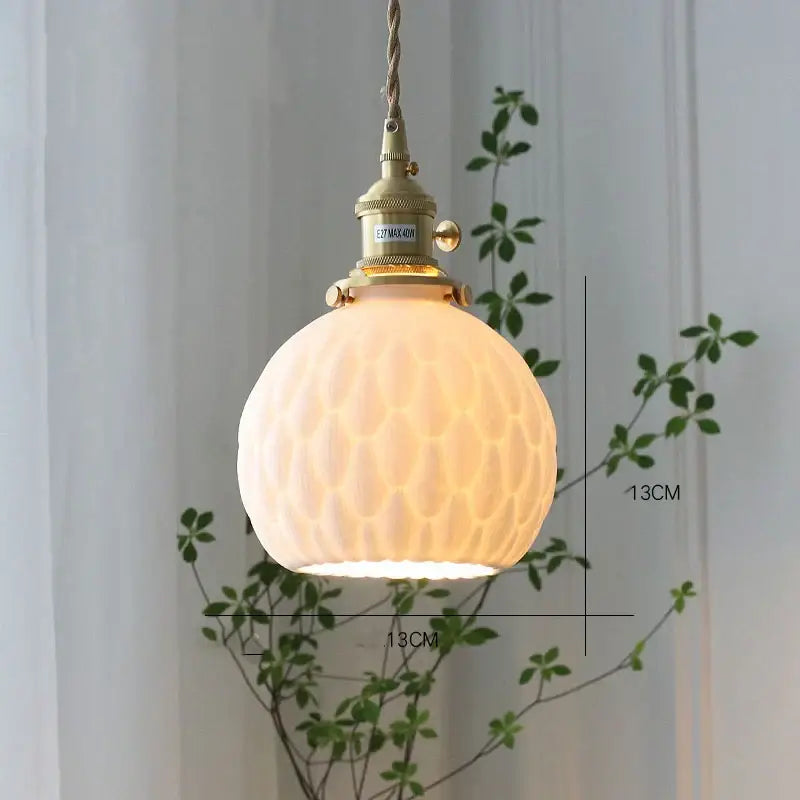 A warm glowing ceramic led wall sconce with textured white glass globe and brass honeycomb decorbites ceramic led design