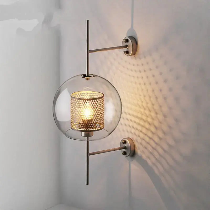 Modern industrial chrome glass wall light featuring a clear glass globe with gold mesh shade and sleek metallic arms for decorbites glass industrial style wall lights