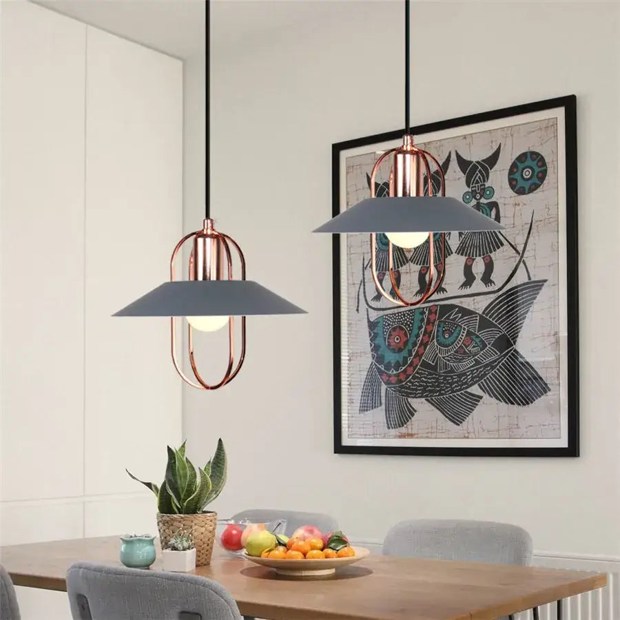 Modern industrial gray pendant light with copper metal frames and matte gray shades hangs above wooden dining table