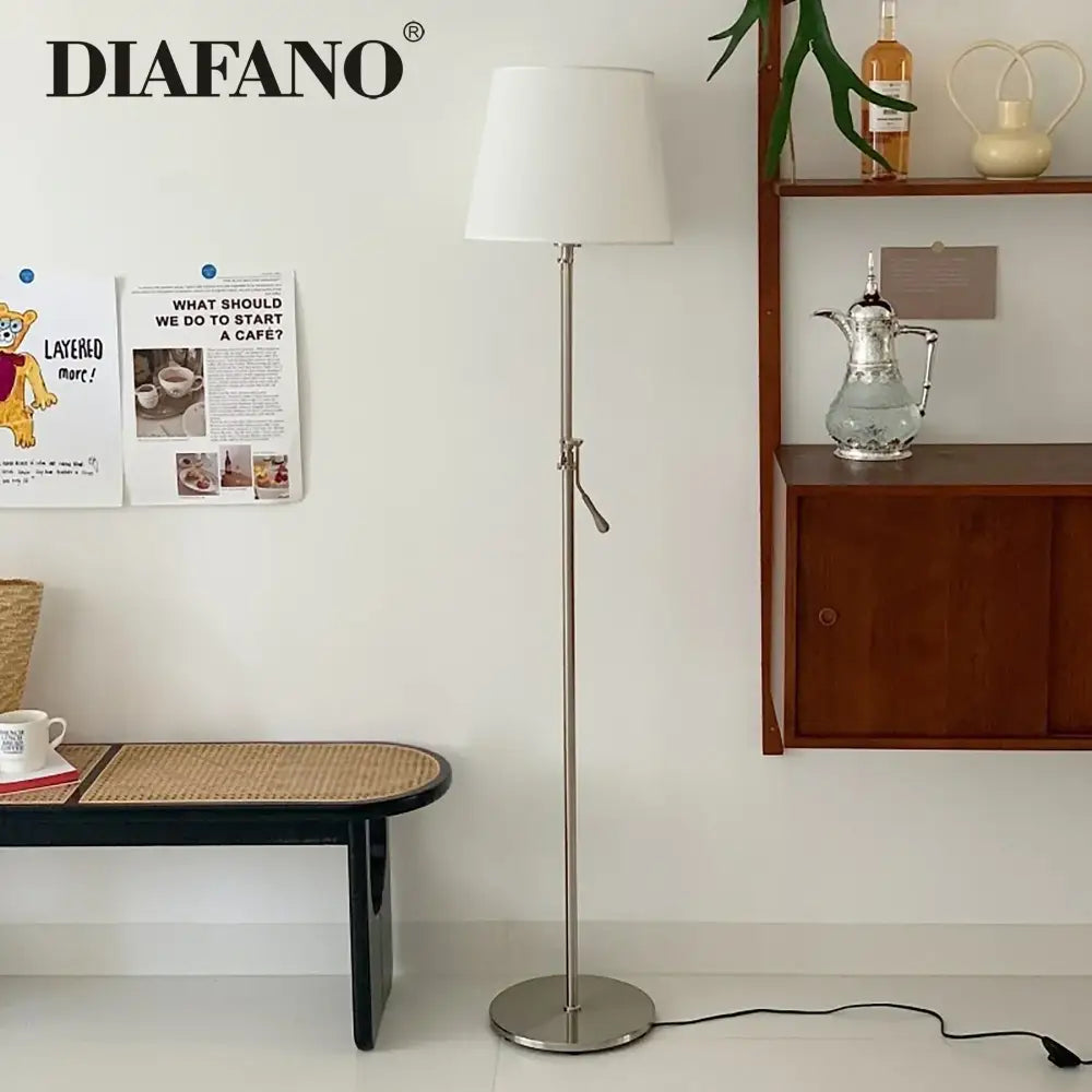 A sleek modern industrial metallic floor lamp with a white cylindrical shade and decorbites adjustable led features