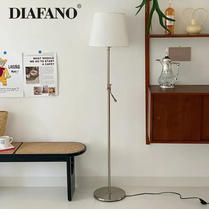 A sleek modern industrial metallic floor lamp with a white cylindrical shade and decorbites adjustable led features