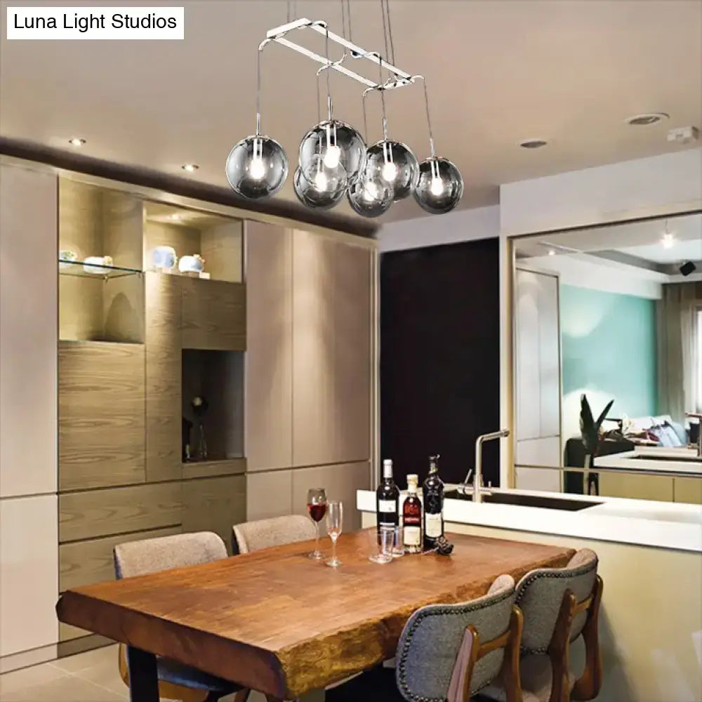 Modern chrome-finished spherical pendant lights with smoke glass hang from a metal frame for island lighting