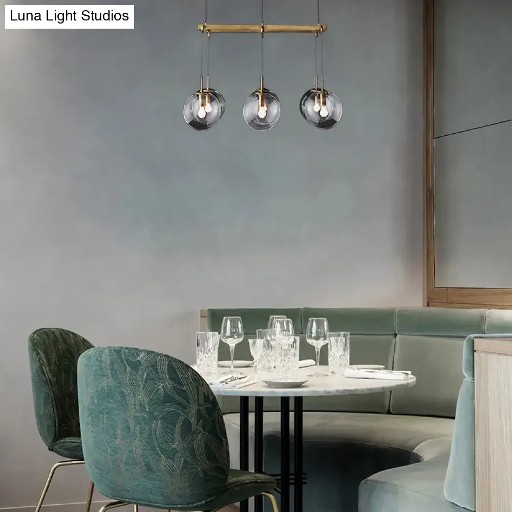 Modern three-light pendant fixture with brass hardware and frosted globes for island lighting with smoke glass accents