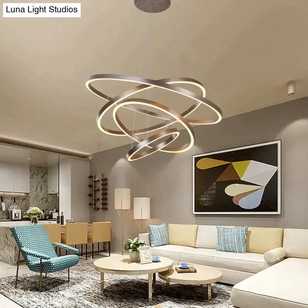 Modern pendant lights featuring a metallic ring chandelier with interlocking circular bands and warm LED lighting for dining room