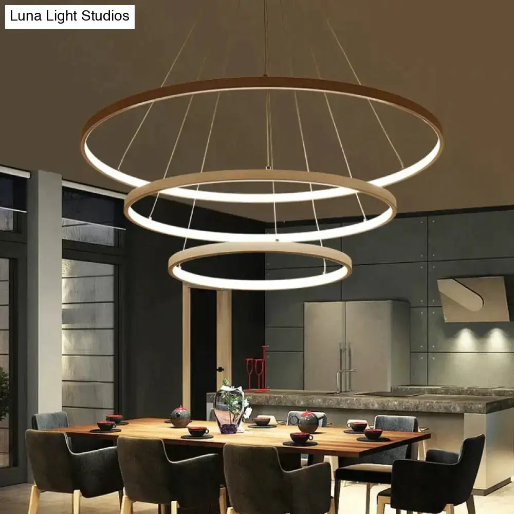 Modern pendant lights featuring three-tiered interlocking circular rings in warm wood with white led lighting for dining room