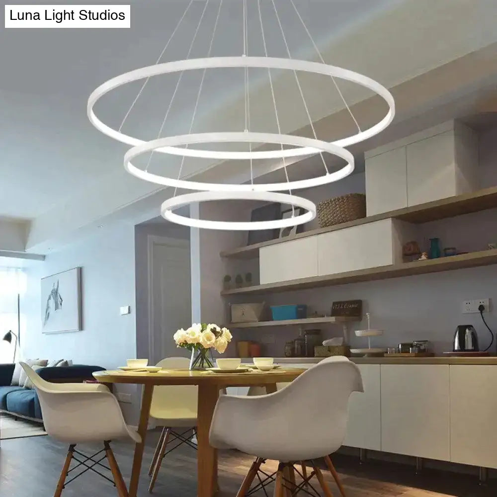 Modern white circular led pendant lights with three concentric rings suspended by thin cords for dining room use