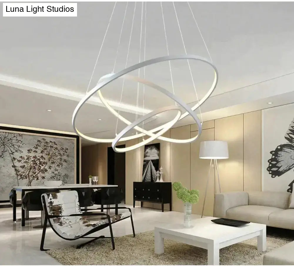 Modern white led pendant lights featuring sleek interlocking circular rings suspended by thin cables for dining rooms