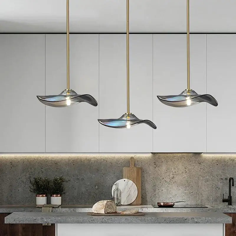 Three elegant wave-shaped glass plated pendant lamps with translucent blue and silver shades for kitchen lighting