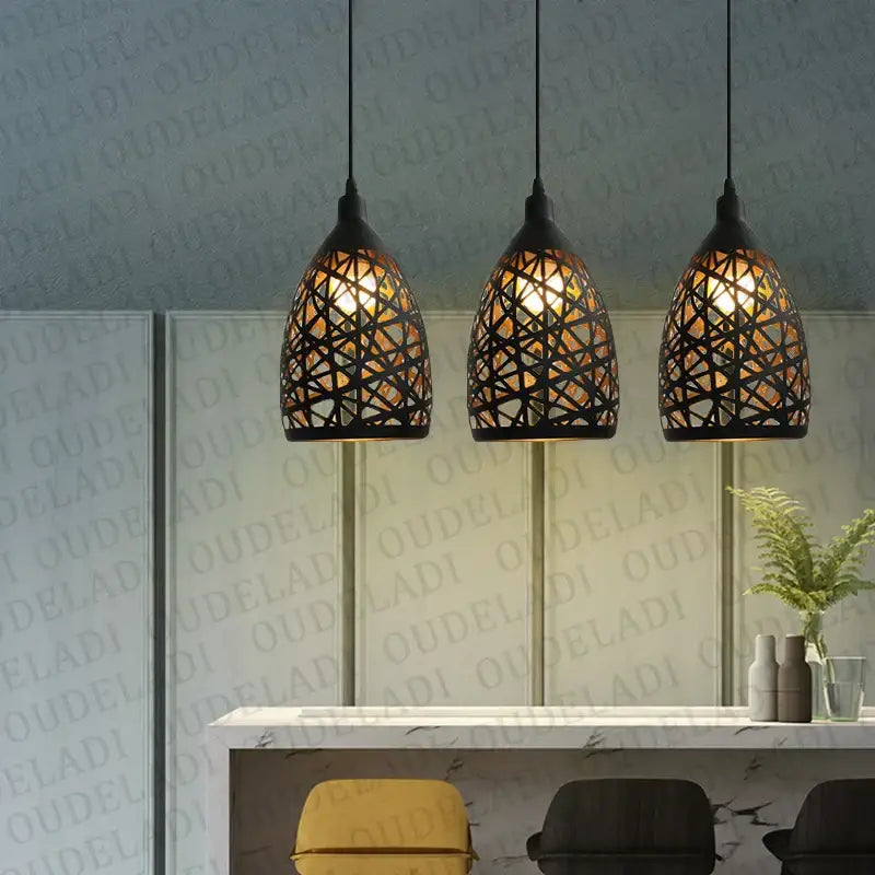 Three black decorbites iron cage pendant lights with intricate woven designs hang above a modern dining room counter