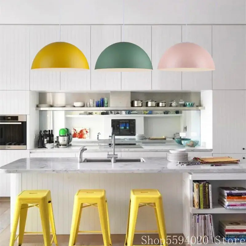 Three colorful matte metal pendant lights in yellow green and pink hang above a kitchen island decorbites iron lustre design