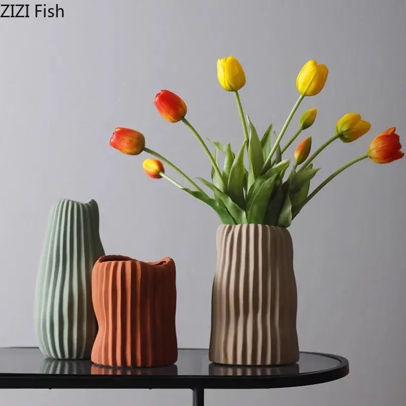 Beige decorbites irregular ceramic vase with vertical ridges holding yellow and orange tulips for living room decor