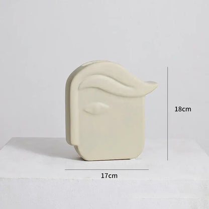 Cream-colored irregular ceramic vase shaped like a stylized human head with sculpted hair by decorbites irregular ceramic