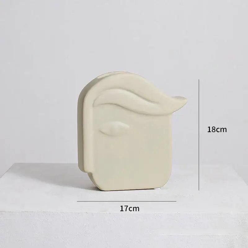 Cream-colored irregular ceramic vase shaped like a stylized human head with sculpted hair by decorbites irregular ceramic