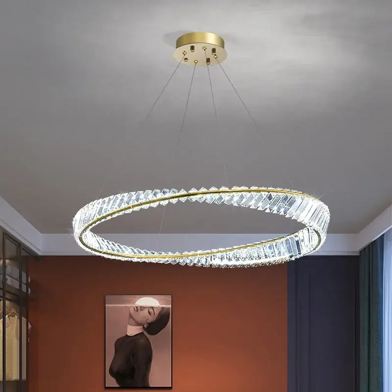 A modern irregular gold steel pendant light with a gold-toned frame and faceted crystal segments for dining rooms