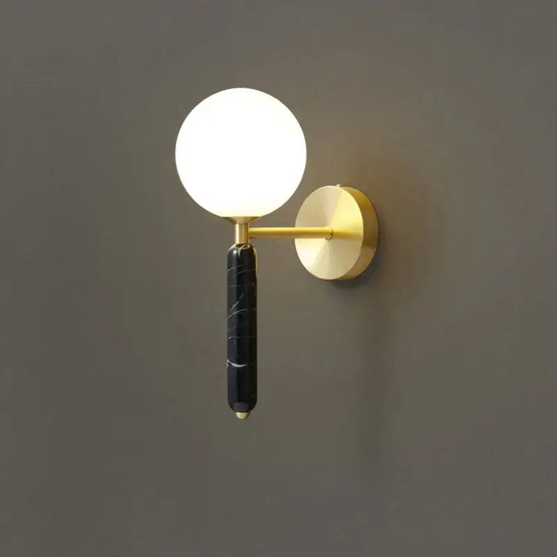 Modern wall lamp with italian green marble stem, spherical frosted glass globe, and gold-toned decorbites italian green accents