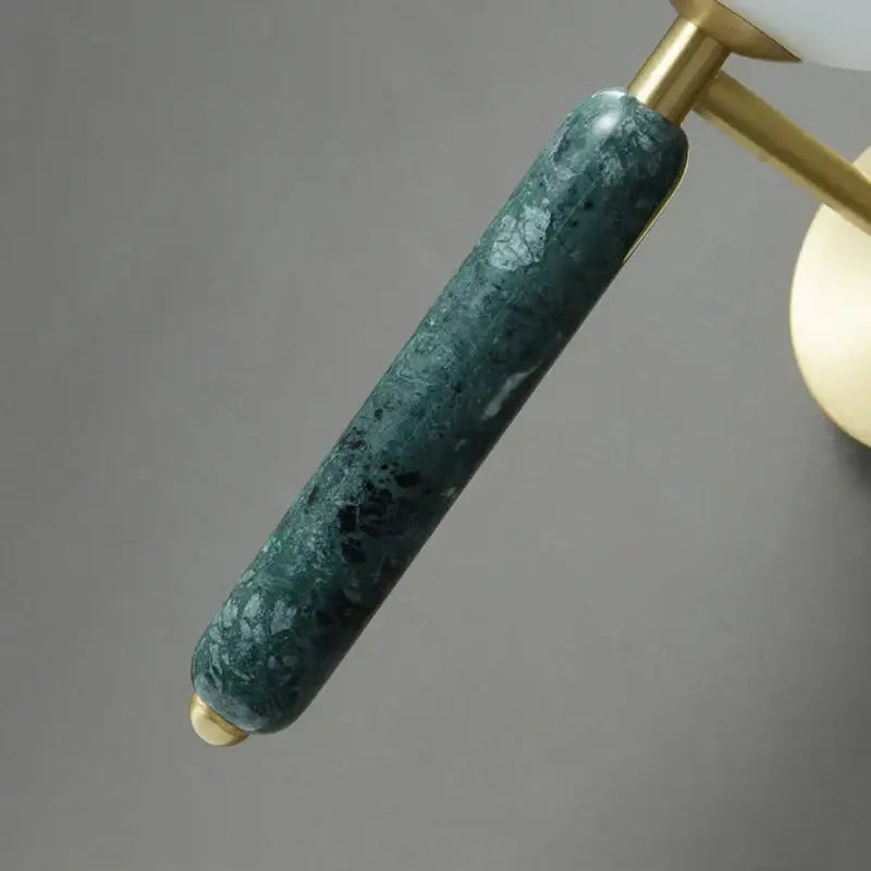 A modern italian green marble wall lamp with a sleek dark green marble arm and gold-toned metal accents