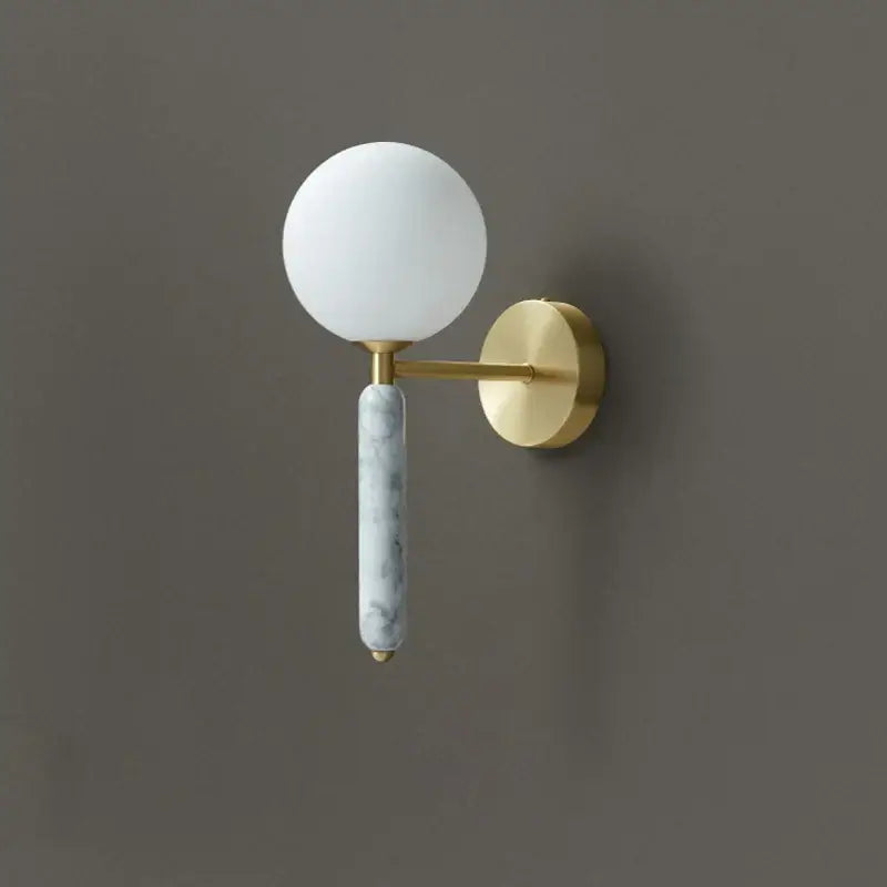 Modern italian green marble wall lamp with frosted glass globe, polished brass arm, and slender marble-textured stem decorbites italian green