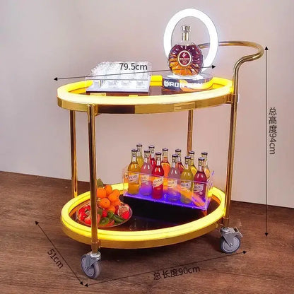 Gold-finished two-tier beauty salon trolley with illuminated yellow led rings and silver caster wheels for salon storage