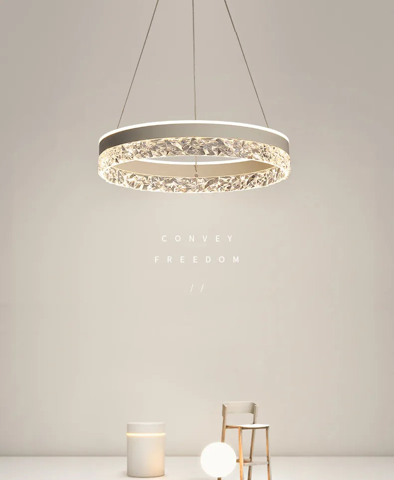 Modern led chandelier with silver frame and faceted crystal ring emitting warm light for living and dining rooms