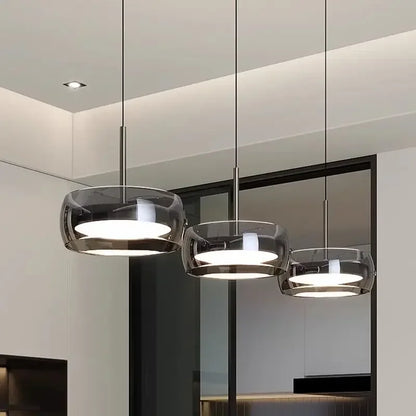 Three modern pendant lights with sleek translucent dark glass shades and polished metal fixtures for indoor decor