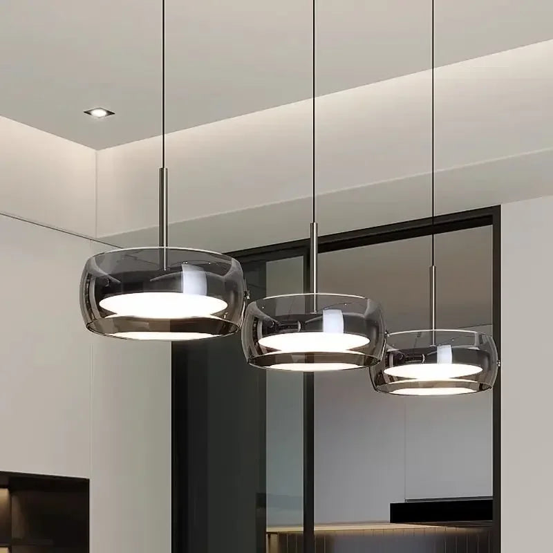 Three modern pendant lights with sleek translucent dark glass shades and polished metal fixtures for indoor decor