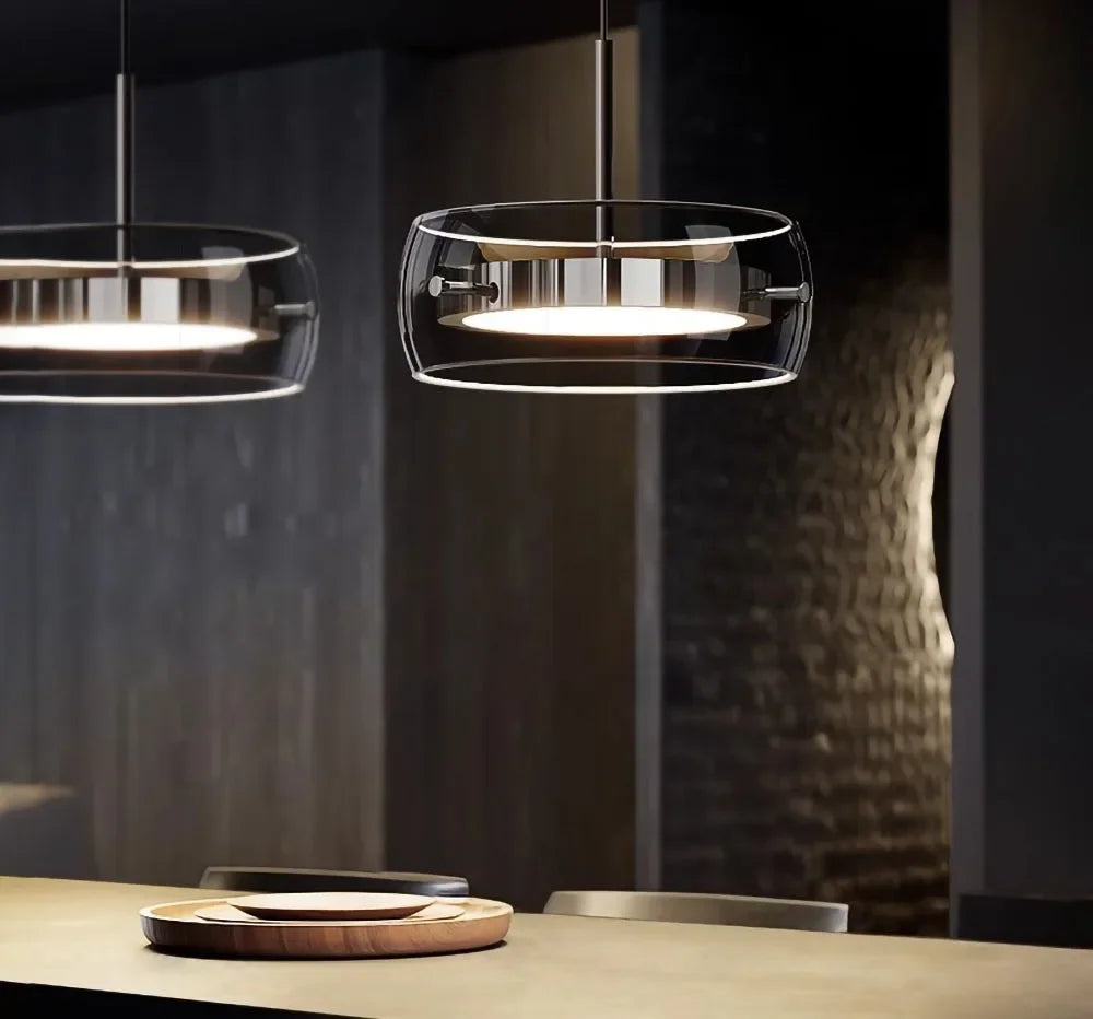 Modern LED glass pendant lights with clear enclosures and brushed metal frames emitting warm light for indoor use