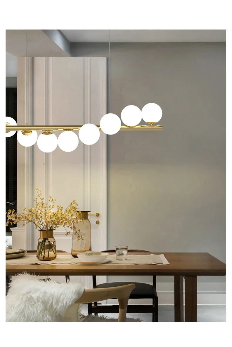 Gold-toned modern LED chandelier with horizontal bar and white glass spherical bulbs for dining room and kitchen lighting