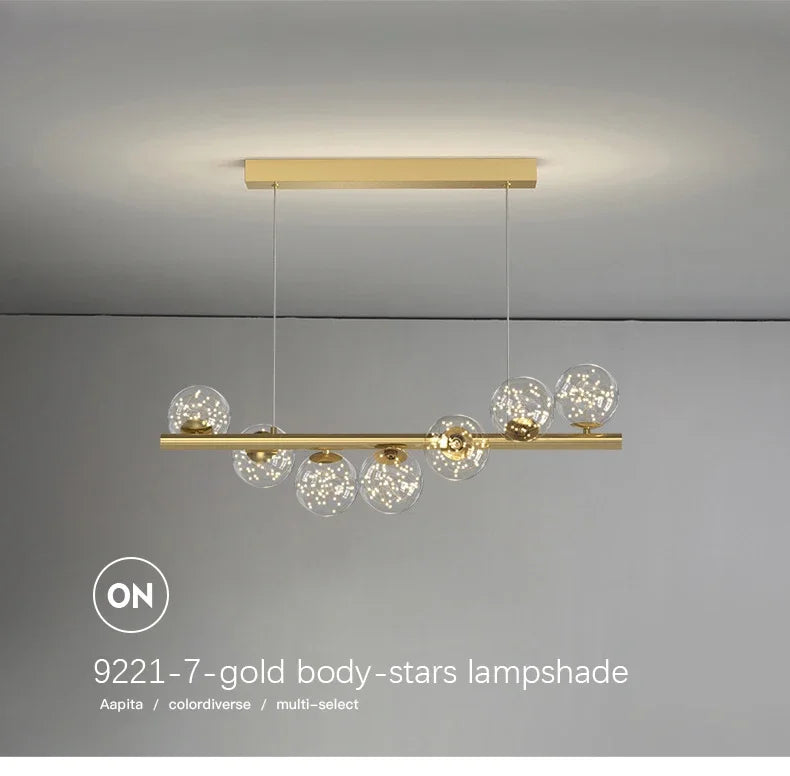 Gold-toned modern LED pendant lamp with a sleek horizontal bar and seven clear glass globe shades with star sparkles
