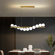Gold-toned modern led ceiling chandelier with sleek horizontal bar and evenly spaced spherical glass bulbs for dining room