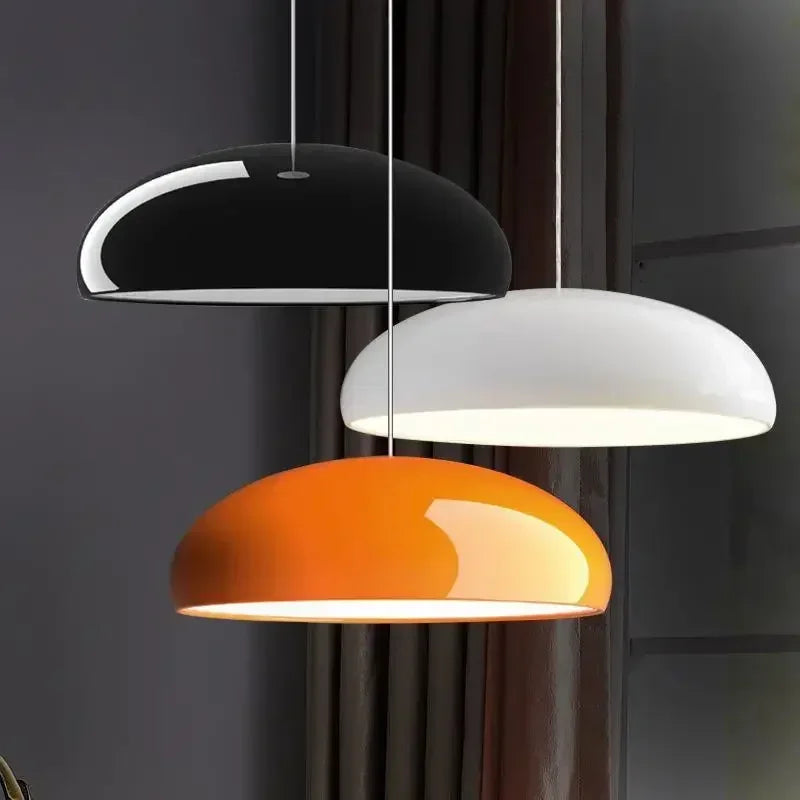 Three modern black white and orange dome-shaped pendant lights with round aluminum lampshades for dining room decor