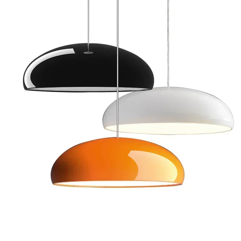 Three sleek dome-shaped pendant lights in black white and orange with round aluminum lampshades for modern room decor