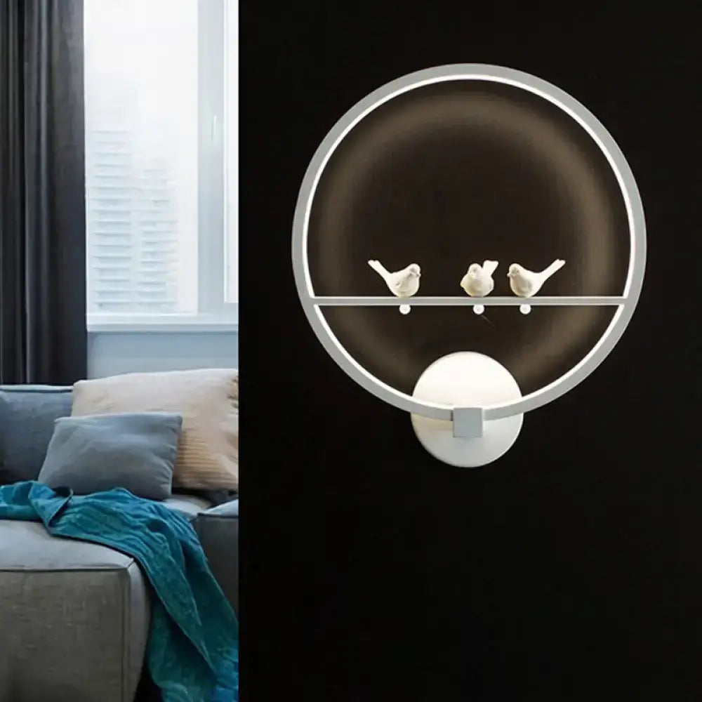 Modern led white wall lamp with circular metal frame and three small white bird figurines for bedroom use